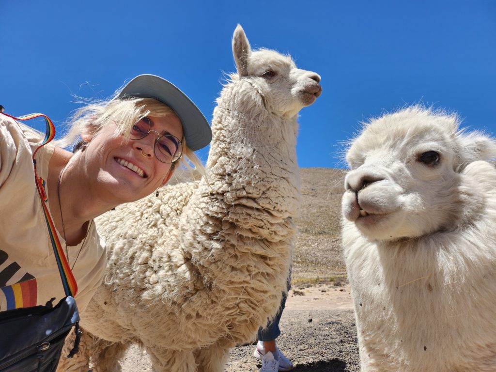 Selfie of Ada with two white alpacas