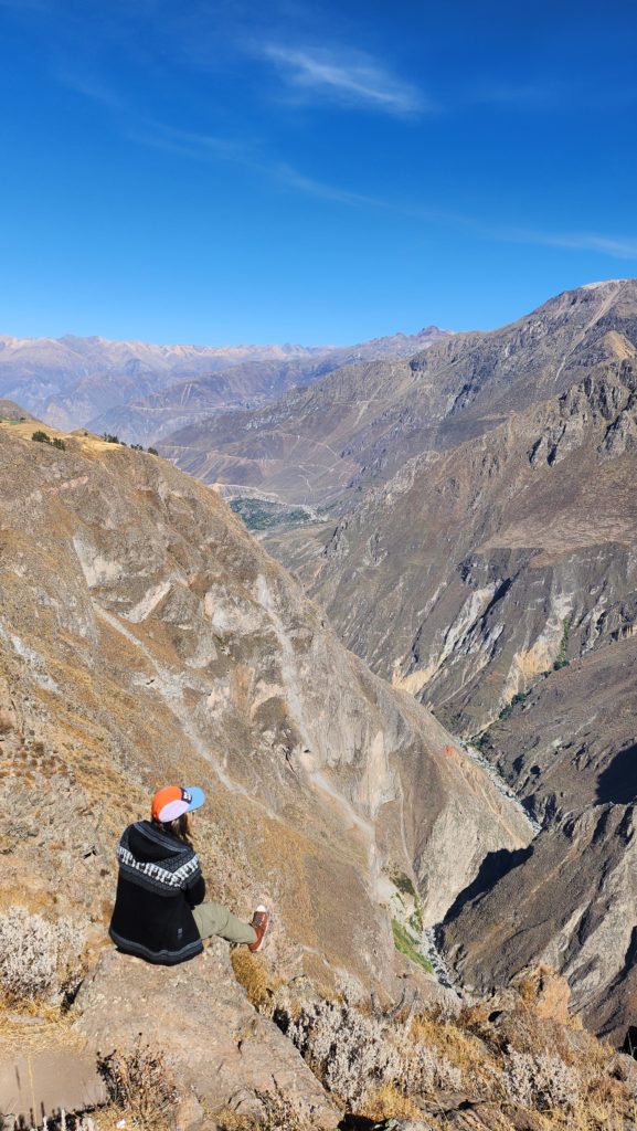 Photograph of Ada sitting on the edge of a cliff overlooking Colca Canyon, Peru.