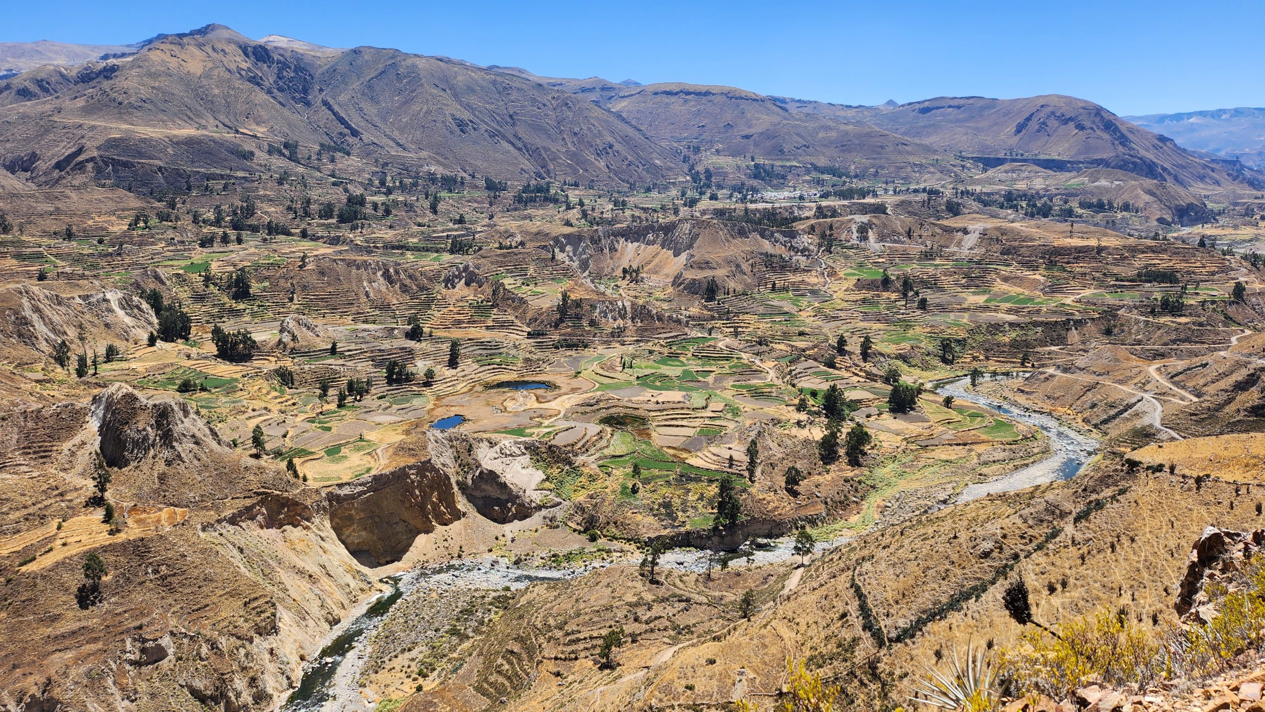 Photo of the Sacred Valley in Peru, an expansive high-altitude valley marked by Inca steppes carved into the mountainside for farming, and a river running through a valley in the foreground.