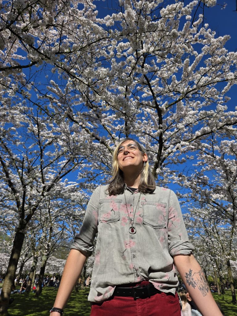 Photo of Ada standing in a forest of cherry blossom trees.