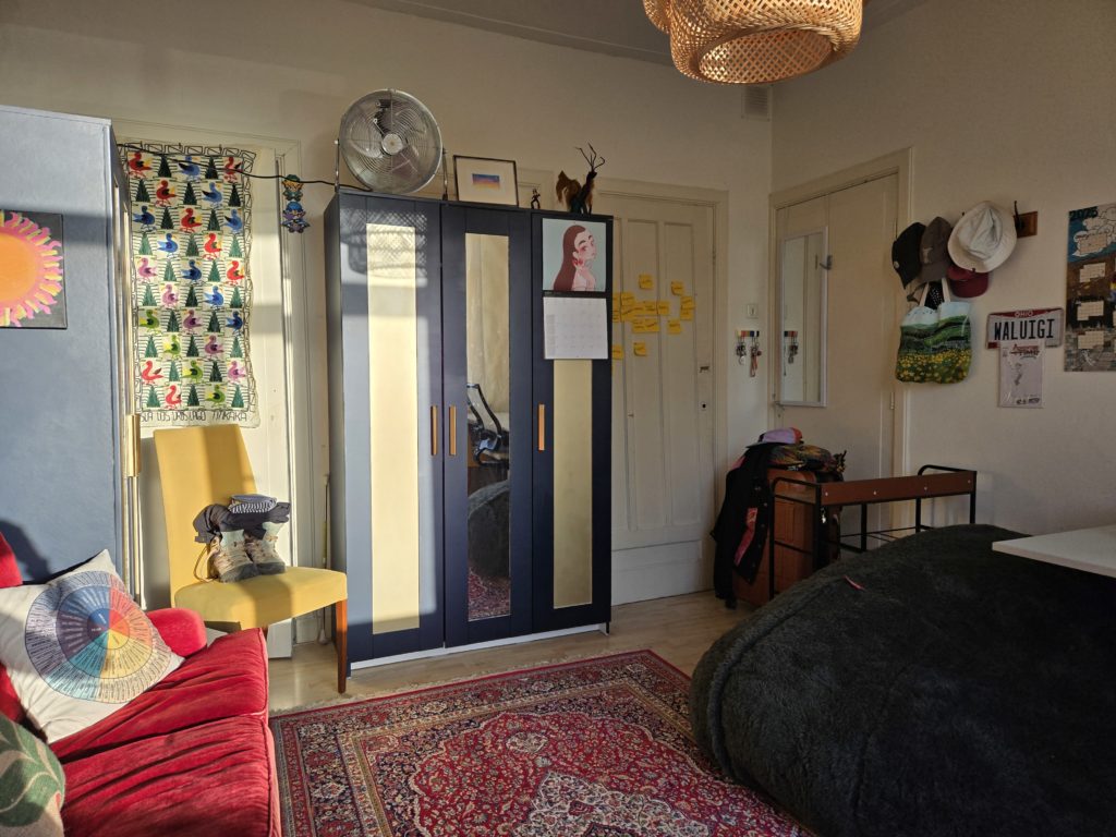 Photo of Ada's bedroom in Haarlem, NL. There are large navy-and-gold wardrobes, a wall tapestry featuring birds and plants, and a beanbag chair.